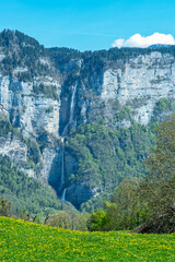 Fototapeta na wymiar View over a beautiful meadow to Seerenbachfall, Switzerland, a high waterfall