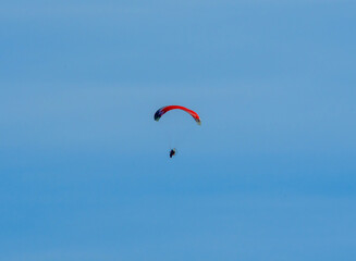 red paraglider paramotor fliers in the blue sky