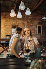 An attractive young woman whispers a secret in the ear of a friend in the restaurant.