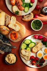 Mediterranean style breakfast plates on terracotta background, top view