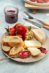 Breakfast plate with cheese, bread, strawberries, and jam, closeup view