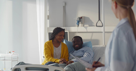 Obraz premium Female doctor talking to african-american couple in hospital room