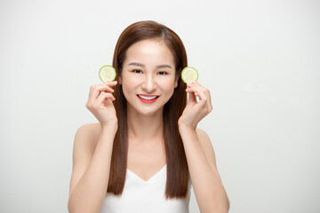 Beautiful joyful Asian woman posing with cucumber and smiling isolated over white background