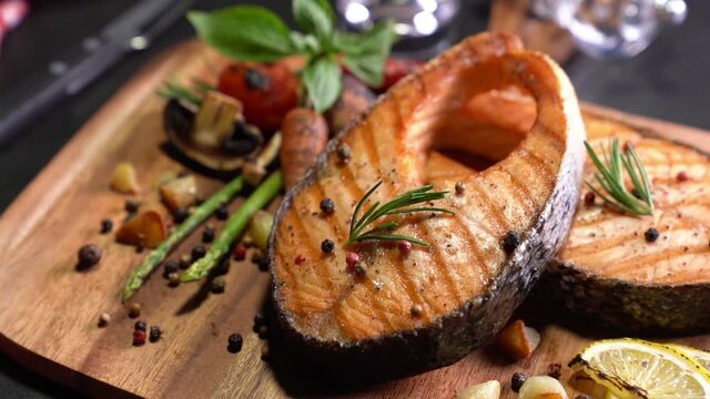 Salmon fish steak with herbs and vegetables on wooden background
