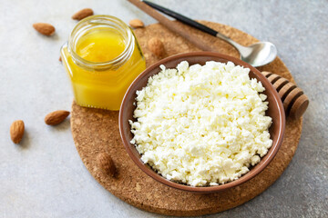 Rich in calcium healthy food. Tvorog, farmers cheese, curd cheese or cottage cheese in a bowl with honey and almond on stone table.