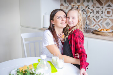 Obraz na płótnie Canvas family, food and people concept - happy mother and daughter having breakfast at home