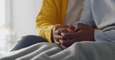 Close up of african wife holds hand of sick husband in hospital