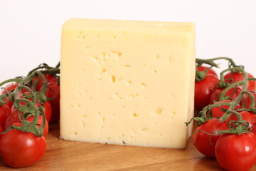 Ein großes Stück Käse auf einem Holzbrett mit Tomaten