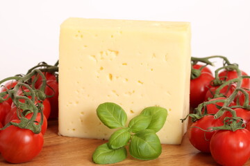 Ein großes Stück Käse auf einem Holzbrett mit Tomaten und Basilikum