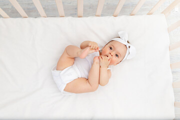 baby is lying in a crib in the children's room on a white bed