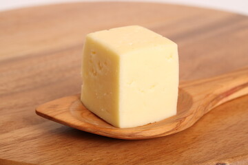 Ein Stück Käse mit Holzlöffel auf einem Holzbrett