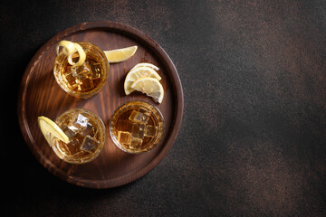 Three glasses of whiskey served on rocks with lemon for festive party on brown background. Copy space. View from above.