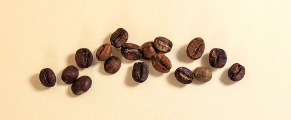 Roasted coffee beans on a beige background.