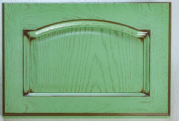 The front of the kitchen door is made of solid oak, covered with green paint and shabby chic varnish. background of decorative woodwork
