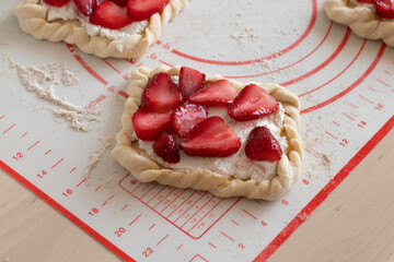homemade food, buns with cottage cheese and strawberry slices, laid out on a silicone mat with...