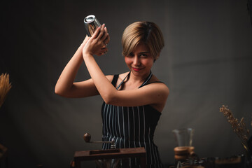 Attractive bartender girl holding in her hands steel cocktail shakers at the bar counter