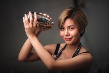 Attractive bartender girl holding in her hands steel cocktail shakers at the bar counter