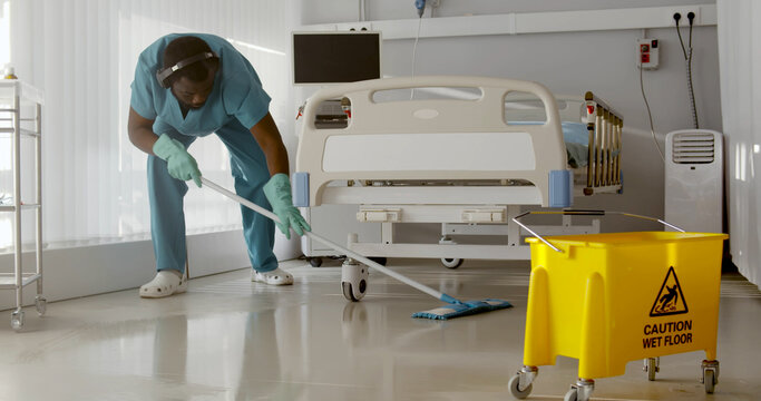 Afro-american male nurse cleaning patient room in modern hospital