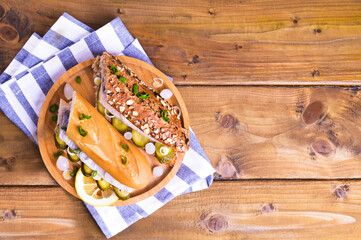 Dutch herring in a sandwich in cereal bread and a white bun. Toast with Dutch herring, onions, pickles. Traditional rustic appetizer with seafood. Popular food in the Netherlands. Copy space
