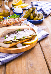 Dutch herring in a sandwich in a white bun. Toast with Dutch herring, onions, pickles. Traditional rustic appetizer with seafood. Popular food in the Netherlands. Copy space. Vertical 