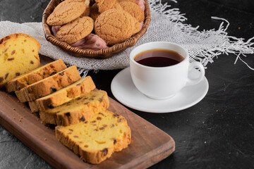 Homemade roulette cake with cup of tea on black background