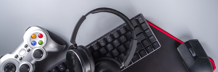 Gaming and gamer devices concept. Gamer work table space background, top view. Keyboard, mouse, gamepad joystick, mouse pad and headphones. on grey table background above with copy space for text © ricka_kinamoto