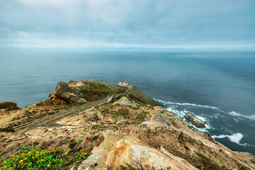 Beautiful landscape, Point Reyes lighthouse on the rocky coast of the Pacific Ocean, a long staircase leads to it. California, USA