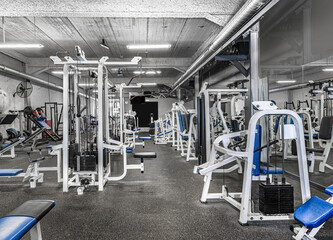 Fototapeta na wymiar Panorama of a classic bright gym. White sport equipment and blue seats. ..