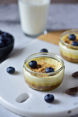 Cheesecake with blueberries in a glass jar, stands on a marble board, in the background a glass of milk.