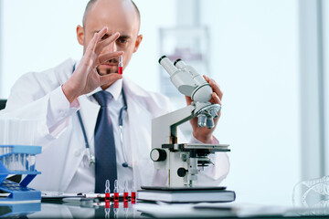 scientist studying vaccine samples through a microscope .