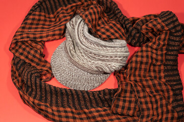 On a red background lies a light checkered scarf and a woman's headdress with a visor.