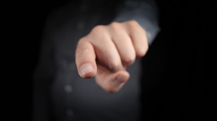 Obraz premium Male hand gesturing. Hand points with the index finger at the camera. Isolated scene against black background