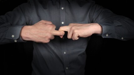 Finger wrestling, hands wrestling, fingers wrestling with each other, businessman does finger wrestling. Man struggles with himself internal conflict, isolated scene against black background