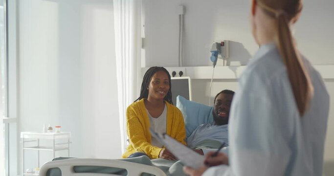 Female doctor talking to african-american couple in hospital room