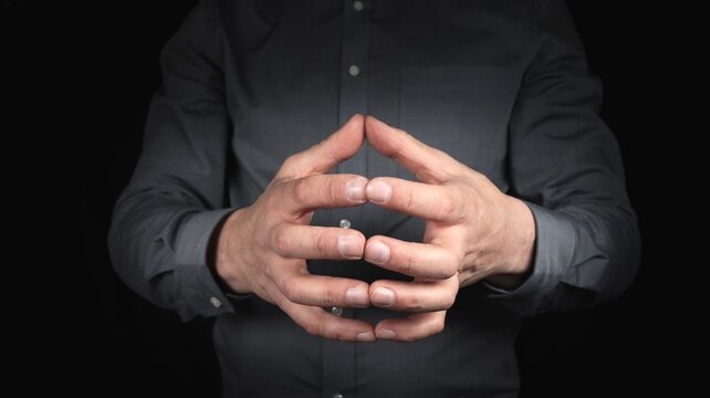 male hands gesture concentration and constructiveness, hands form a roof with a gesture, black background