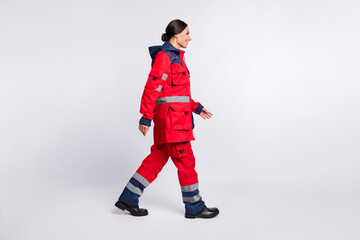 Full length body size profile side view of nice cheerful girl doc rescuer walking isolated over grey pastel color background