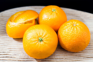 Oranges on wooden bowl with black background