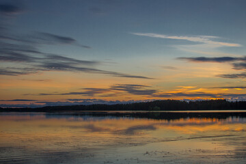 Beautiful sunset landscape over a Finnish lake. The space is flooded with gold.