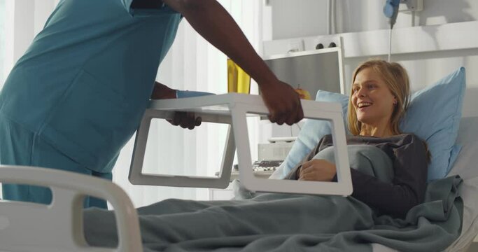 African man nurse serving food in hospital to patient in bed