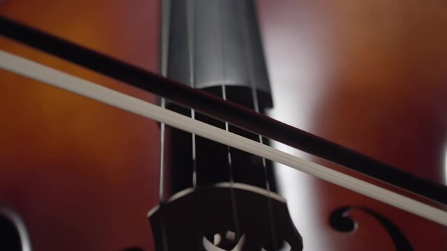 Artist plays with bow on strings of the cello close-up. Musician plays on the cello with hand and bow. Stringed musical instrument