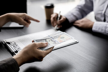 The businessman is pointing at the contract signing box and holding the dollar bills, he is forcing the purchasing manager to sign a contract together to defraud the company, fraud is illegal.