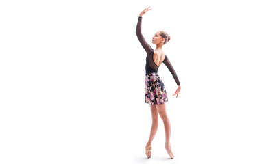 A young ballerina in pointe shoes poses in a graceful pose isolated on a white background