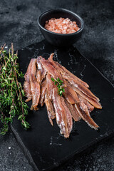 Anchovies fish fillet in Olive Oil. Black background. Top view