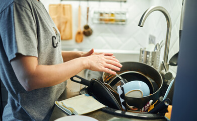 Young woman washing dishes in the kitchen. Home work