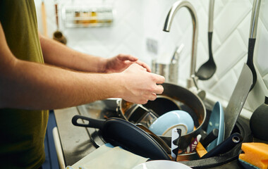 Young man washing dishes in the kitchen.