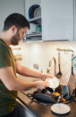 Young man washing dishes in the kitchen.