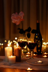 Romantic composition with burning candles and wine on table home at night