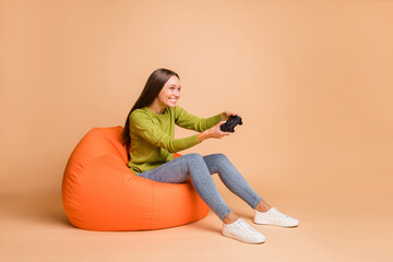 Profile side view portrait of lovely cheerful girl sitting on chair playing video game pastime...