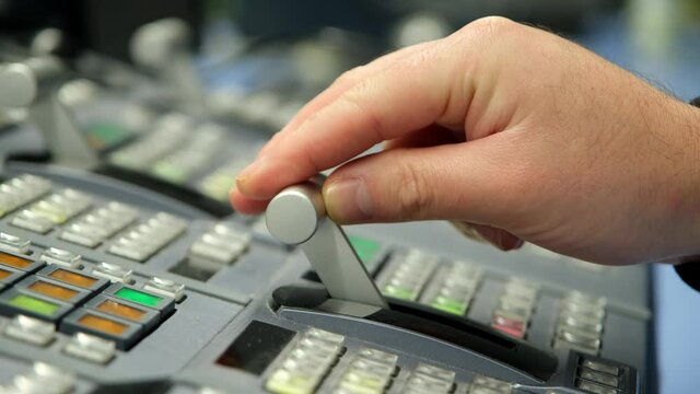 Hand adjusting on switcher buttons in studio TV station, Television Broadcast.