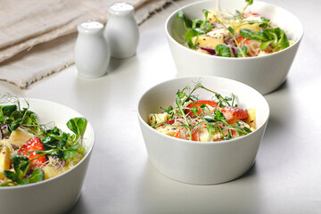 Fruit salad with strawberries, pineapple pieces, herbs, red onions and cheese in white ceramic bowls on a light background. Ideas and recipes for a healthy diet. Vegeterian food. Organic nutrition